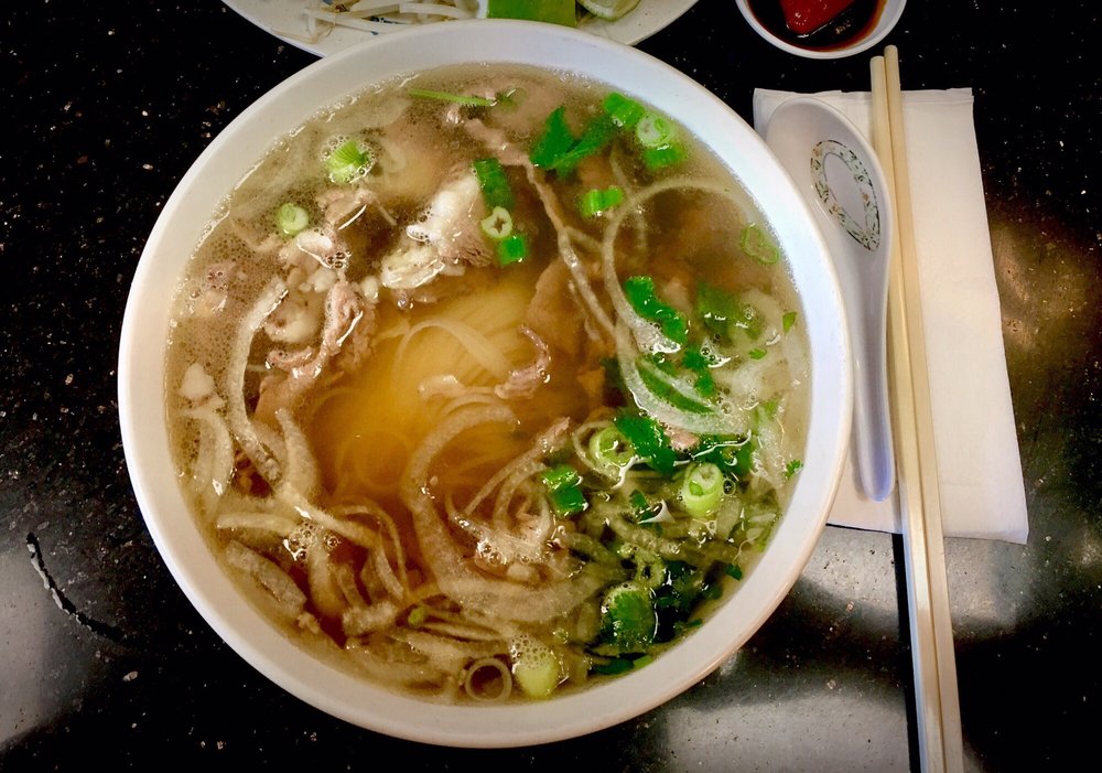 Bowl of pho with clear broth, noodles and green onion