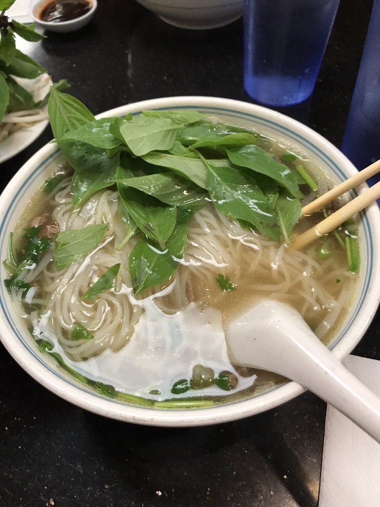 Pho topped with Thai basil, chopsticks resting on the bowl