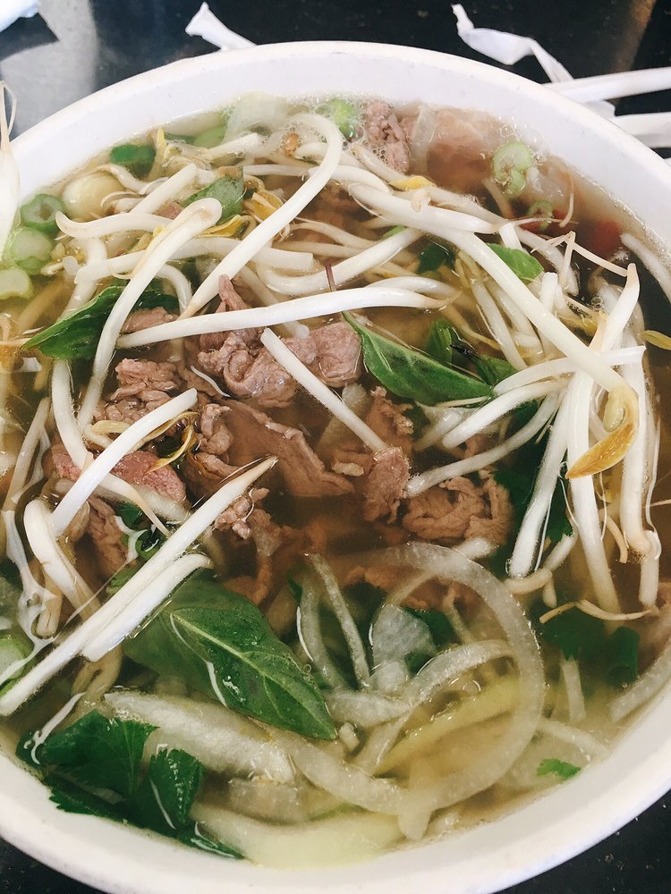 Bowl of pho with sliced beef, bean sprouts, basil and onion